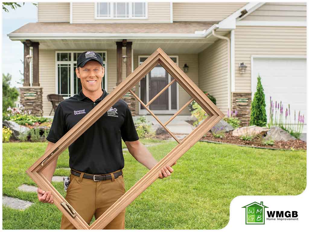 installation tech holding new window in front of house