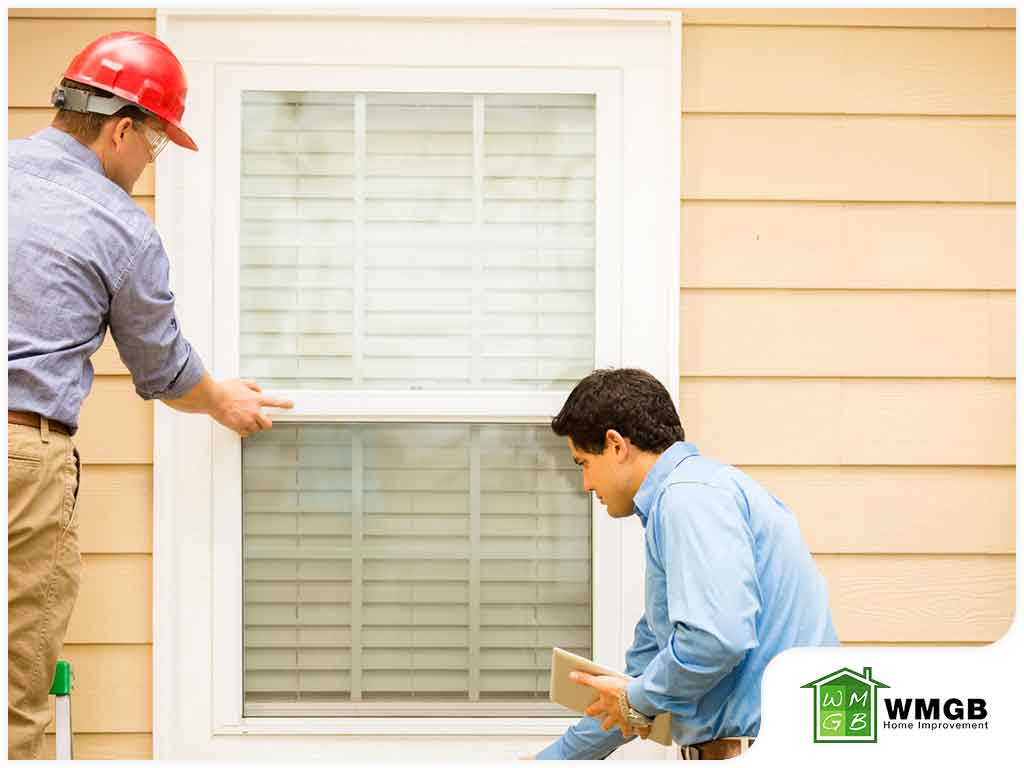 2 men inspecting exterior of windows on house