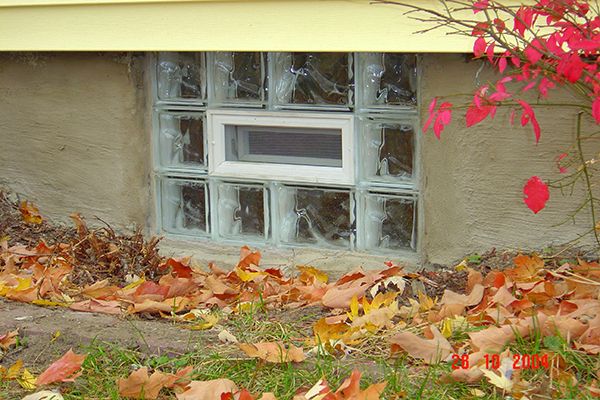 glass block basement window with autumn leaves