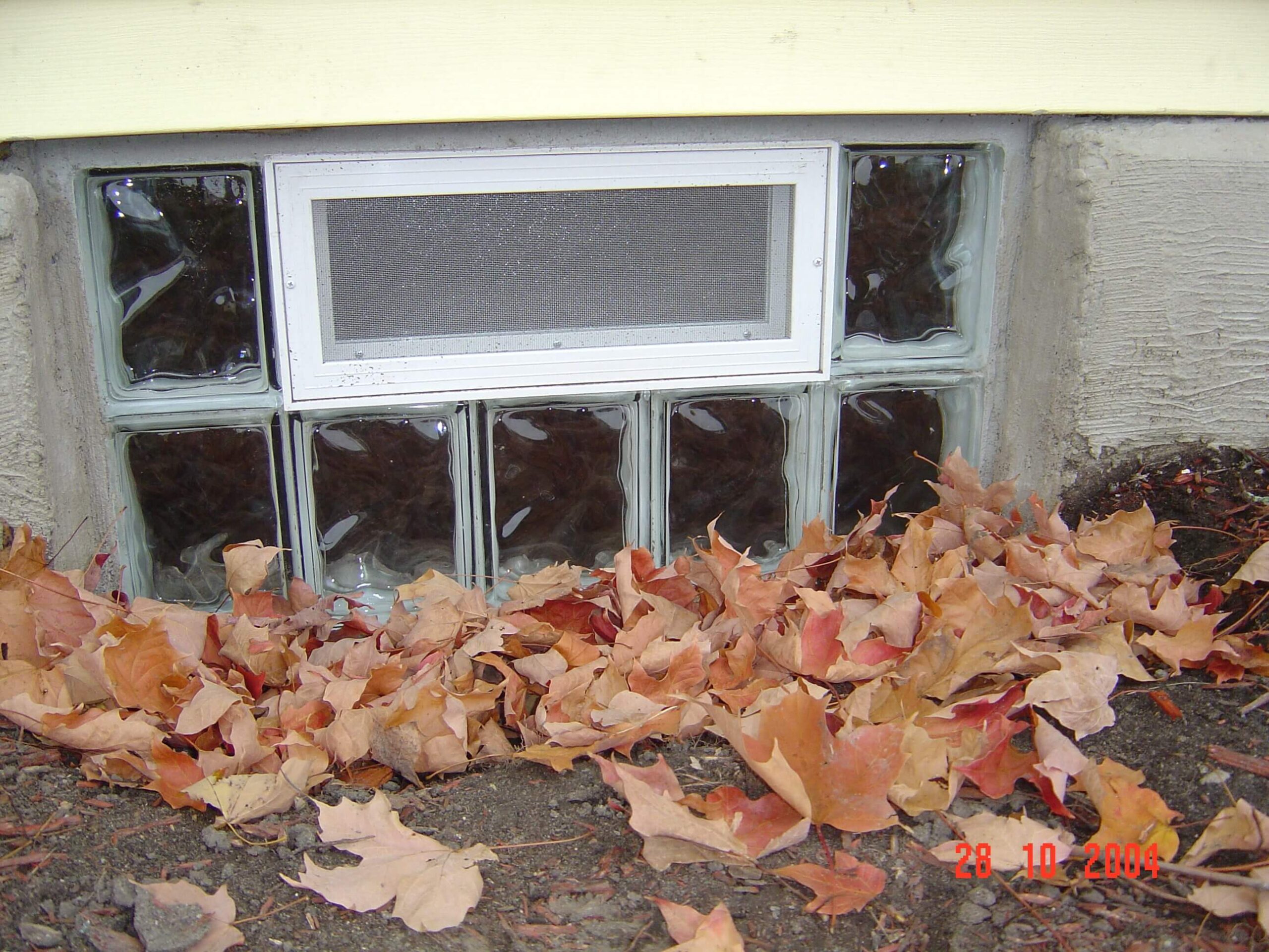 glass block basement window in autumn