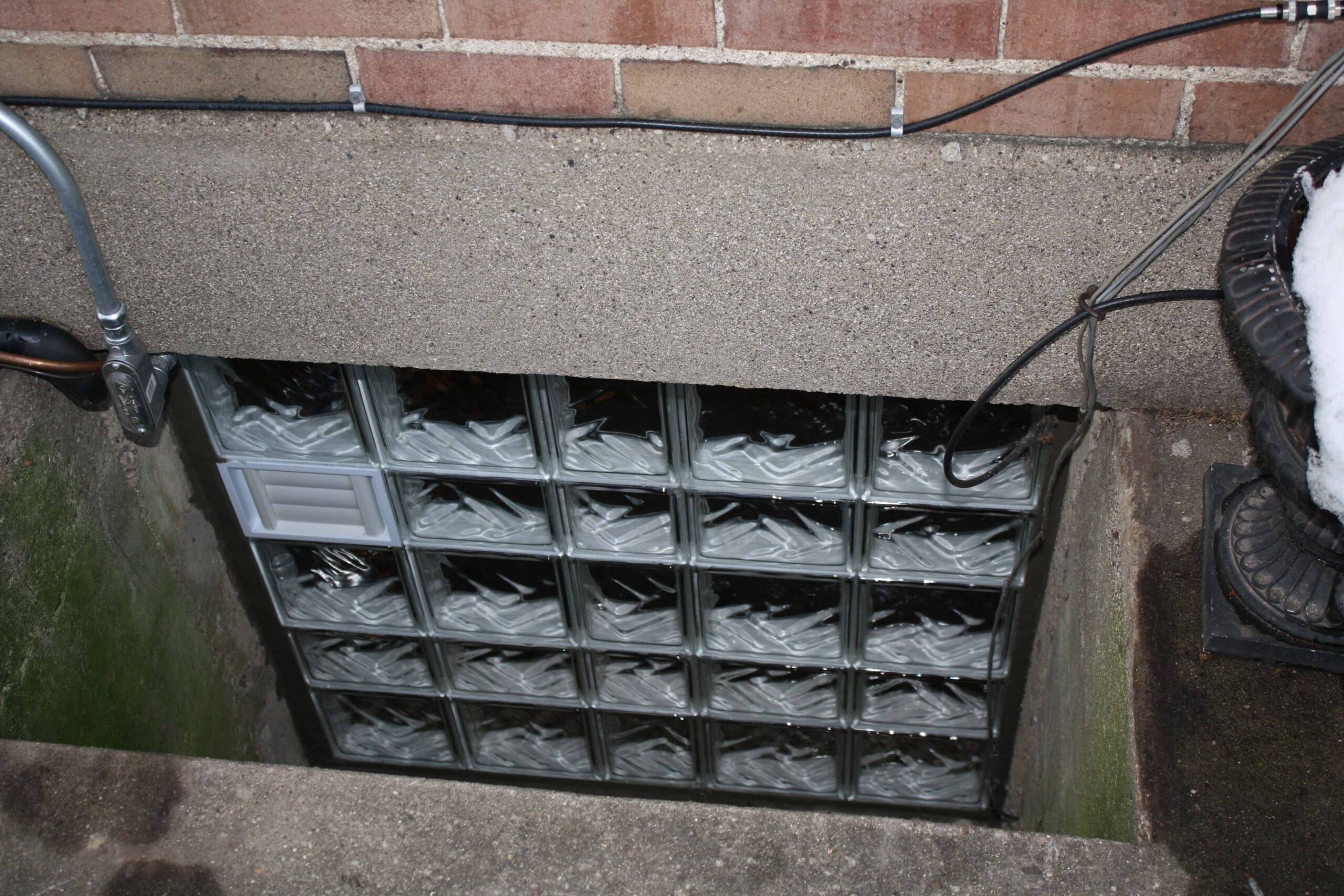 glass block basement window in a deep well